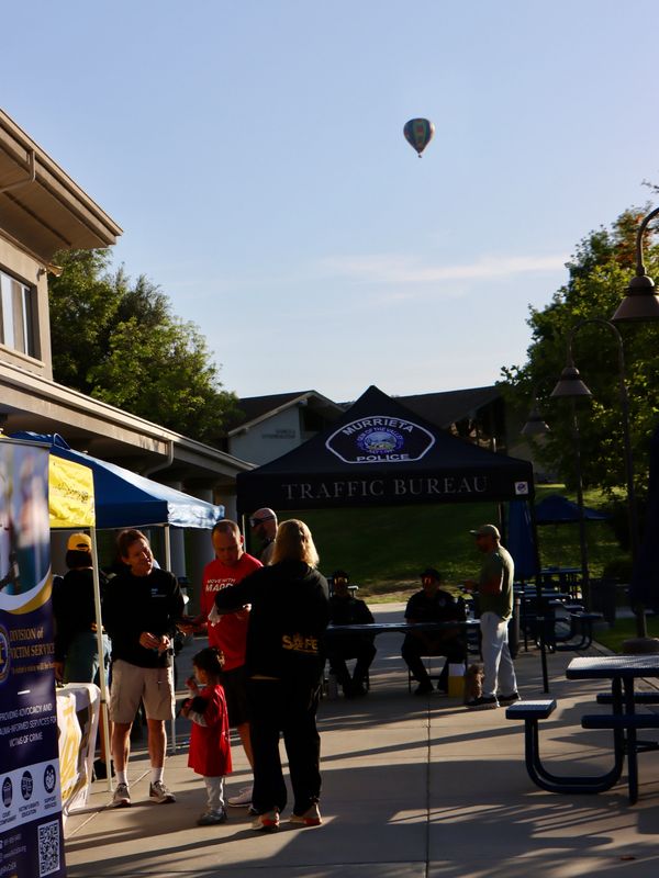 Community event with Murrieta Police Traffic Bureau tent and hot air balloon in the sky.