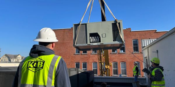 K&B Plumbing and Heating crew lowering by crane commercial HVAC unit