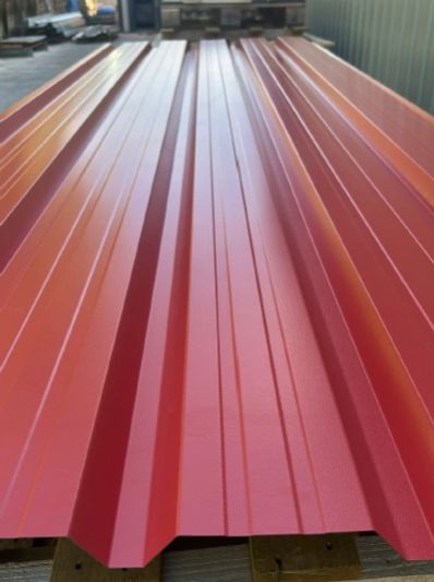 Bright red corrugated metal roofing sheets stacked outdoors.