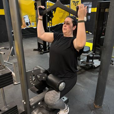Woman exercising on gym lat pulldown machine.