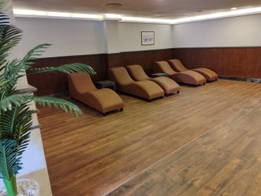 A calm lounge area with four brown chaise lounges and wooden flooring.