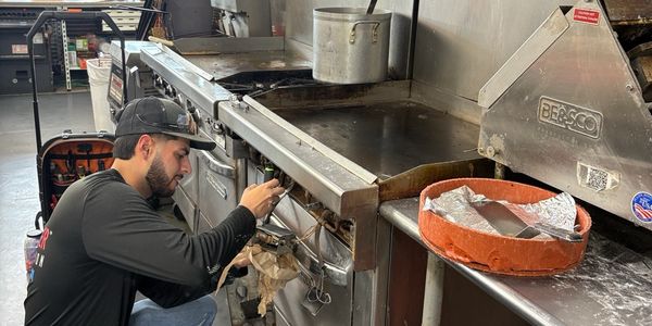 Technician repairing a commercial Southbend stove inside a convenience store kitchen