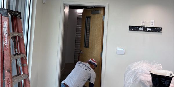 Technician performing interior repairs and finish work inside a commercial building.