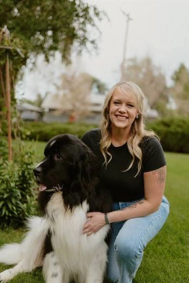Woman kneeling beside a large black and white dog outdoors.