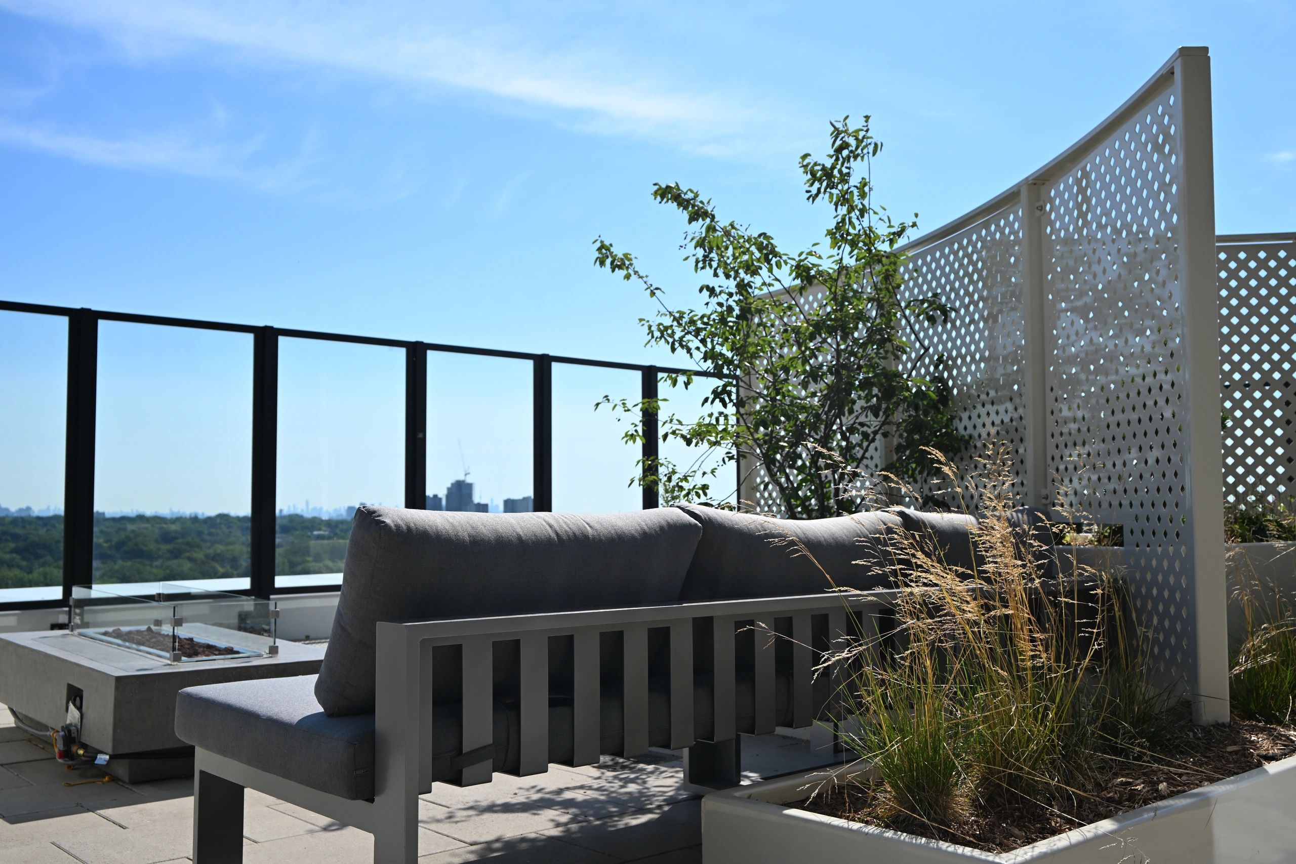 Cozy outdoor seating area on a rooftop with city skyline view.