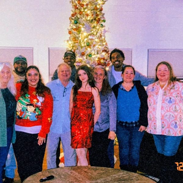 Family and friends gathered in front of a decorated Christmas tree.
