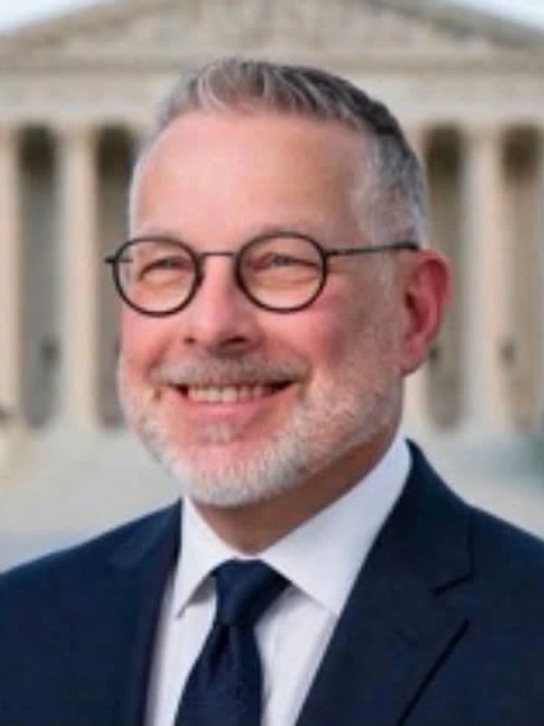 Smiling man with glasses in a suit.
