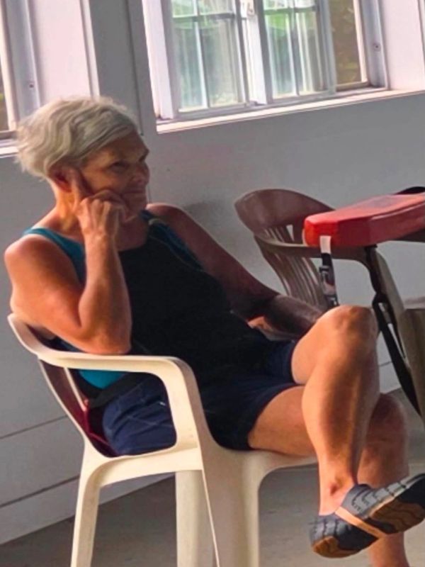 Elderly woman sitting and talking on phone indoors.