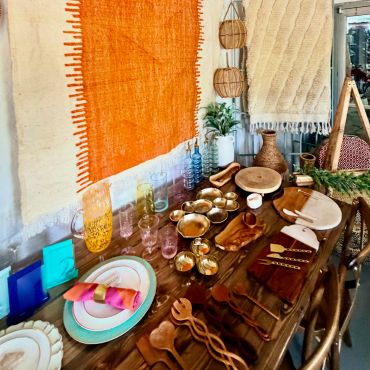 Rustic table setting with colorful glasses and wooden utensils.