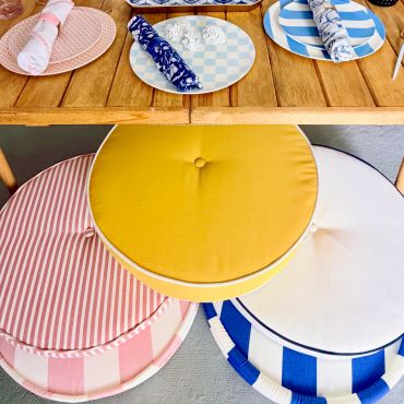 Colorful round cushions and patterned table setting on a wooden table.