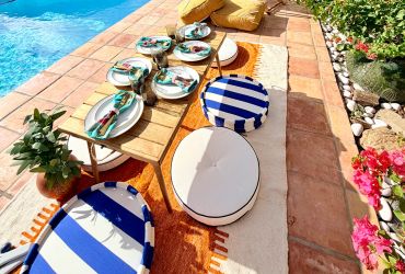Poolside low table setup with striped and white cushions for outdoor dining.