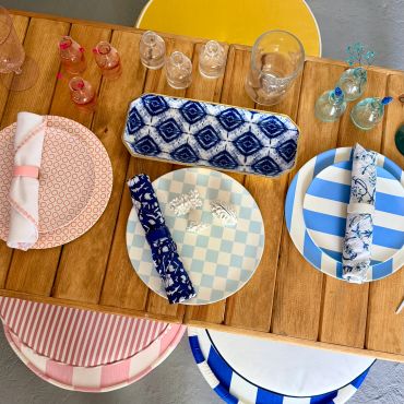 Colorful table setting with patterned plates, napkins, and glasses.
