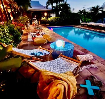 Cozy poolside seating with loungers and soft lighting at dusk.