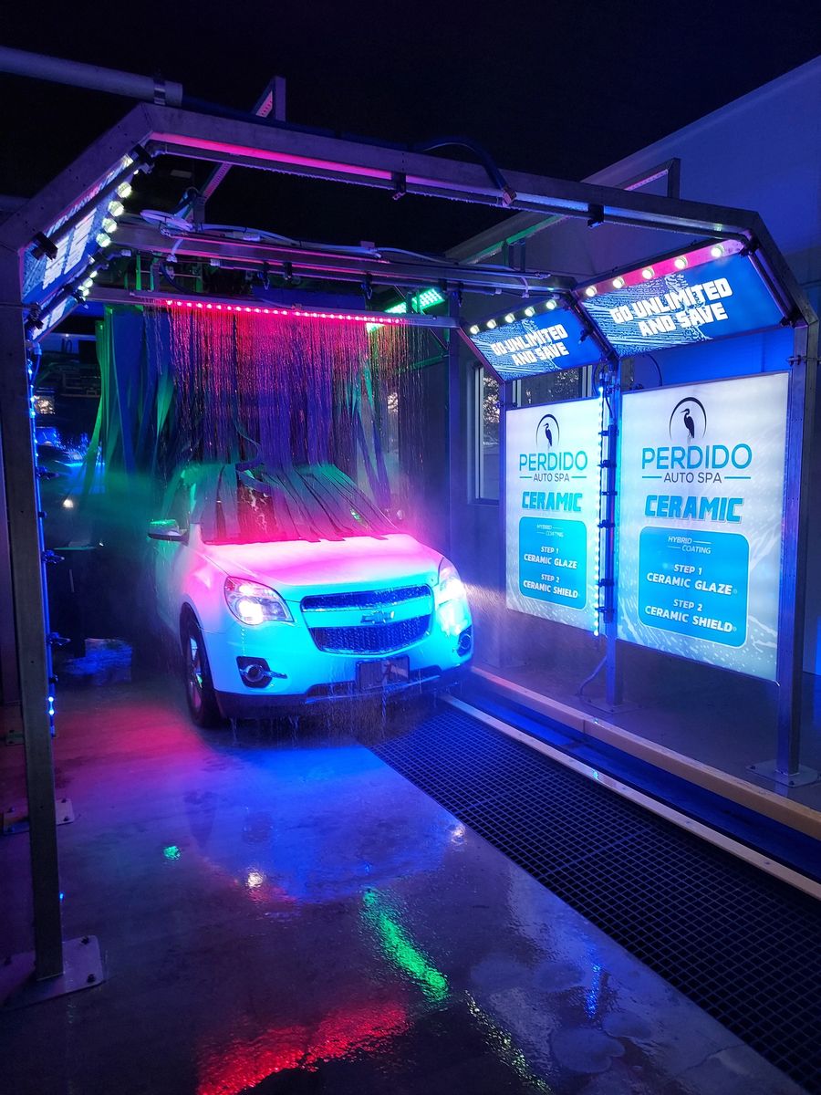 Car going through the lit-up Perdido Auto Spa wash tunnel