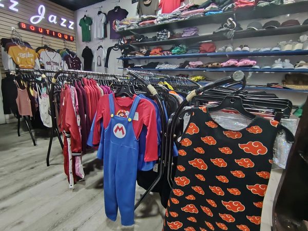 Clothing racks in a boutique featuring colorful outfits and shelves with folded clothes and shoes.