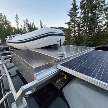 Inflatable boat and solar panel on a metal platform surrounded by trees.