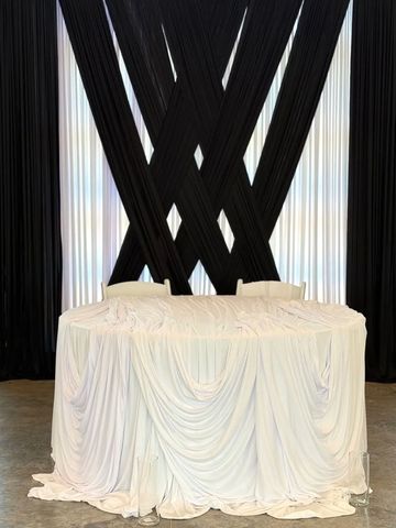 Table draped with white cloth and black curtains behind.