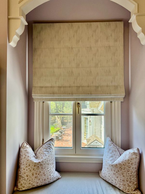 Window seating nook with cushions and a beige shade.