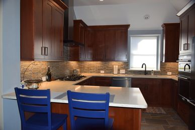 kitchen designed with dark wood cabinets and white counter tops and dark appliances