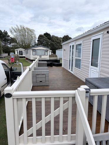Deck area with white railings and outdoor seating at mobile homes.