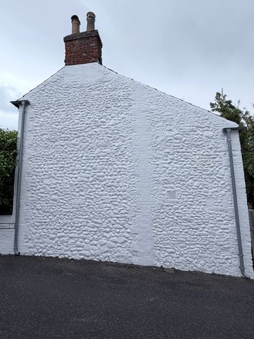 White-painted stone wall of a house with chimneys.