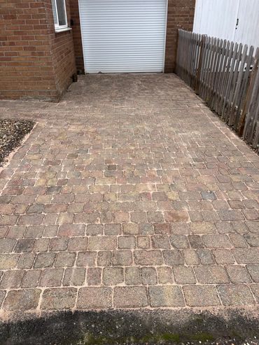 Stone-paved driveway leading to a white garage door.
