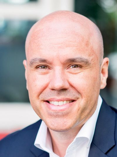 Smiling bald man in a suit jacket and white shirt.