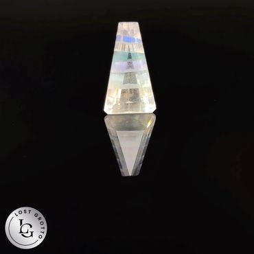 A clear, prism-like crystal reflecting light against a black background.