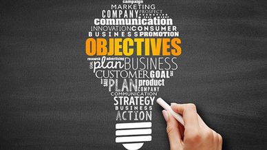 Lightbulb word cloud highlighting 'Objectives' in business strategy.