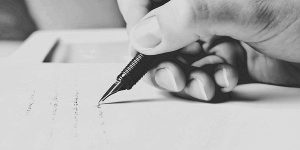 Una persona escribe con una pluma profesional en un papel 