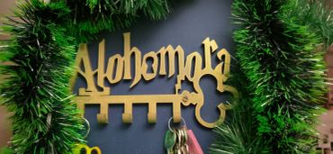 Chaveiro dourado com palavra "Alohomora" decorado com guirlanda verde.