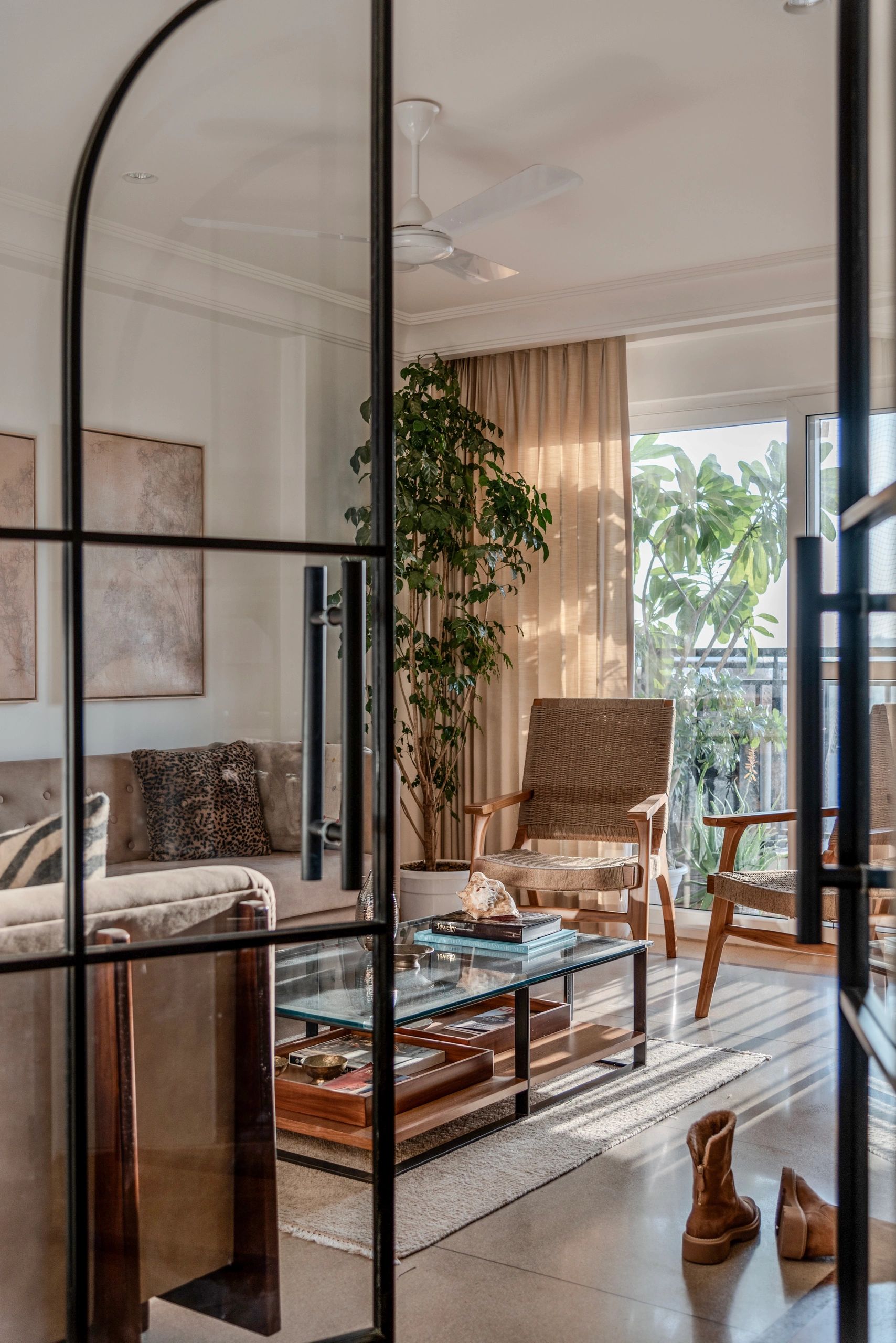Cozy living room with natural light, plants, and warm-toned furniture.