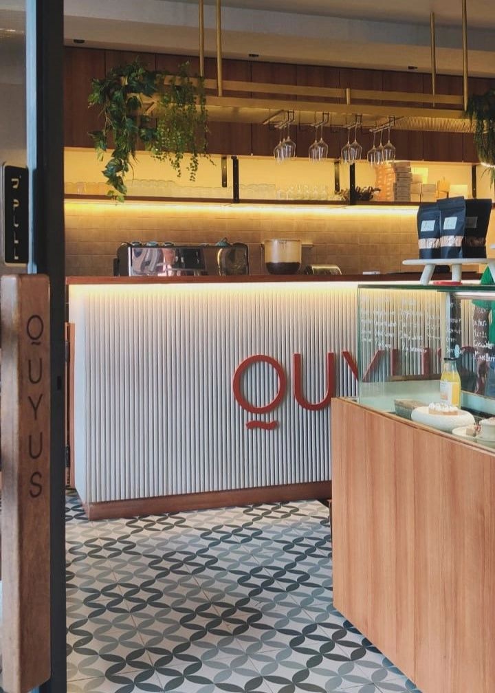 Cozy modern cafe interior with patterned floor and hanging plants.