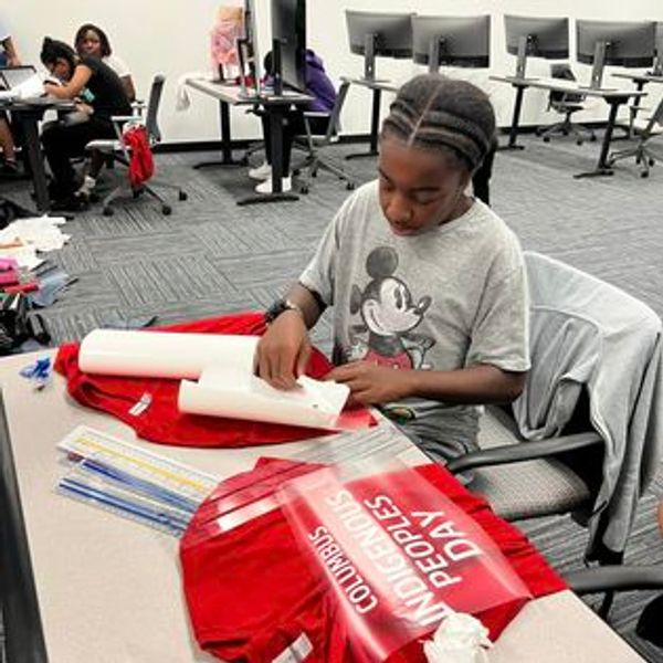 A child working on a craft project with red materials in a classroom.