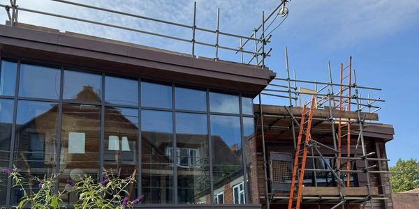 Building under construction with scaffolding and glass windows.