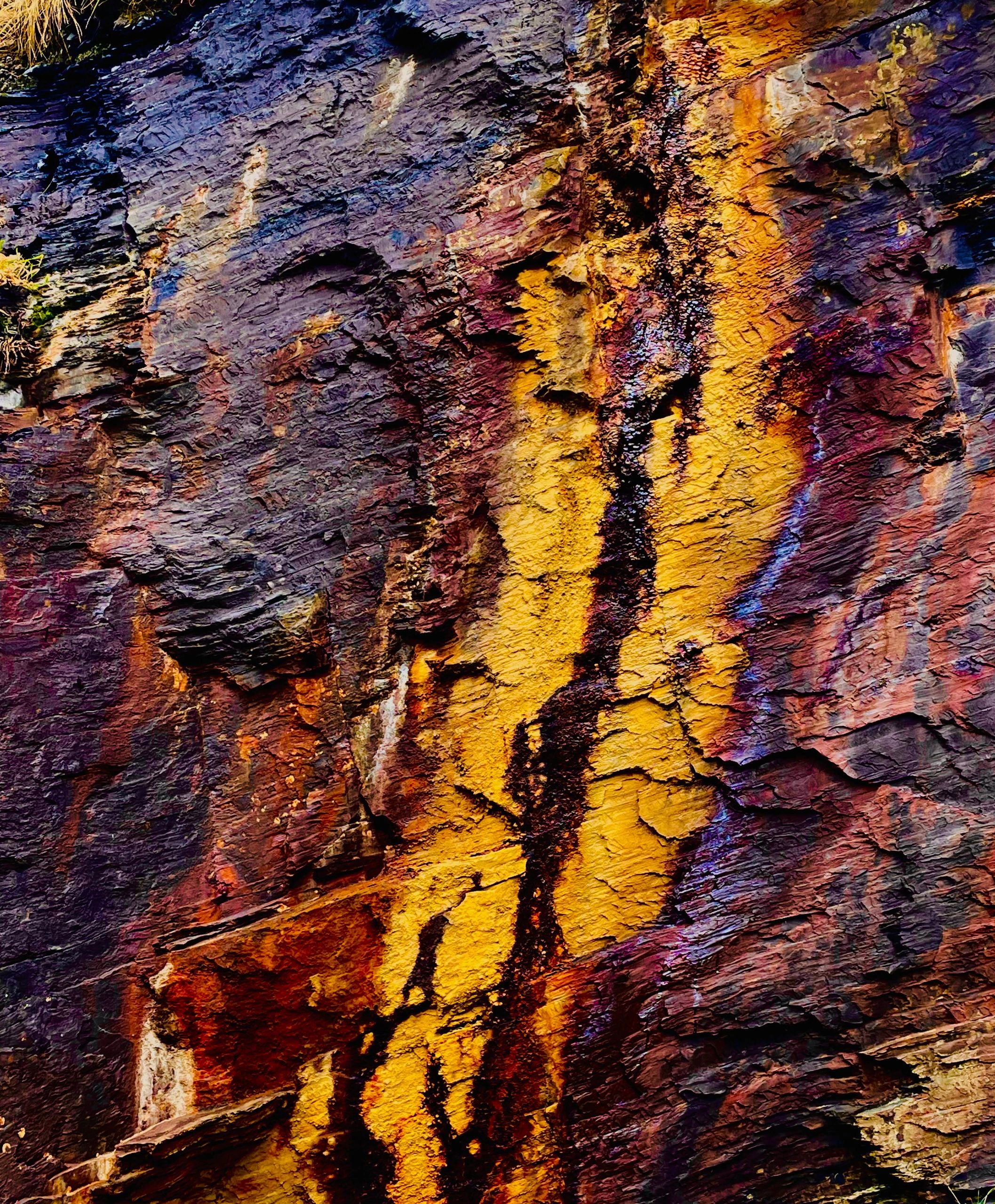 Close-up of colorful rock formations with vivid yellow and purple hues.