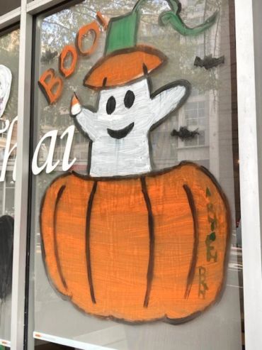 Halloween-themed window painting with ghost and pumpkin.