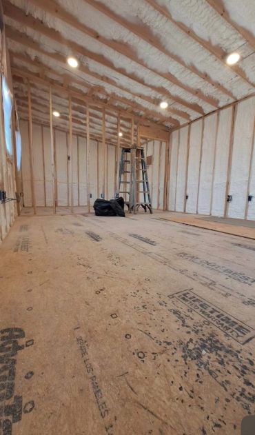 Room under construction with foam insulation and wooden framework.