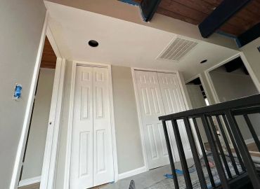 Interior hallway with closets and a black railing.