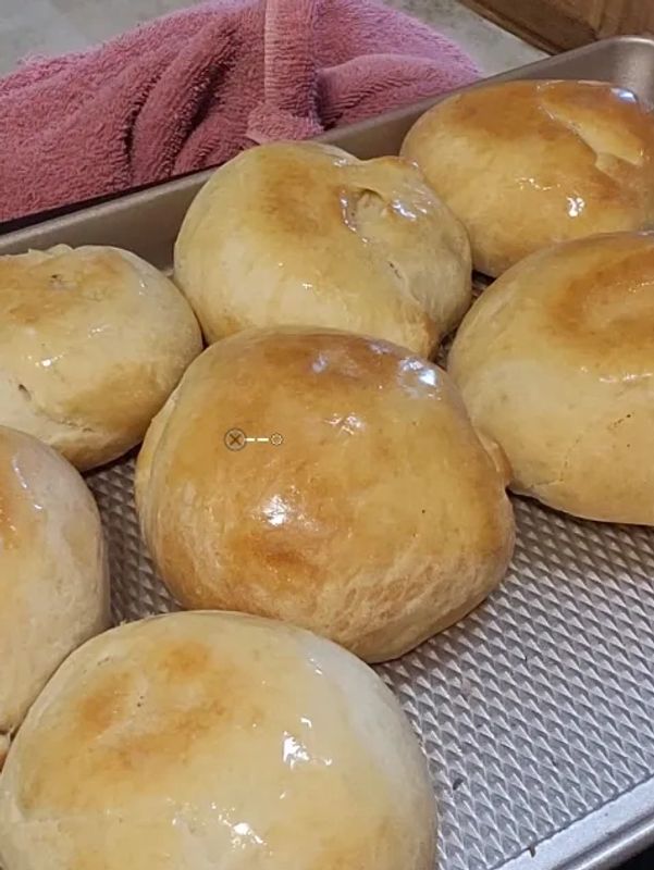 Freshly baked golden brown bread rolls on a baking tray.