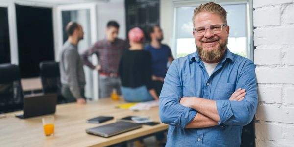 Smiling man with glasses standing confidently in an office.