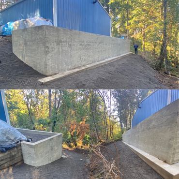 Newly constructed concrete retaining wall beside a blue building in a wooded area.