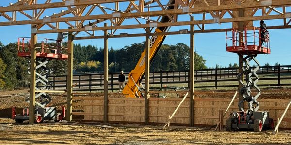 Construction workers using lifts to build a wooden structure outdoors.