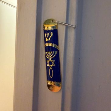 Blue and gold mezuzah on a doorframe.