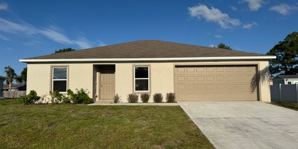 Single-story beige house with a two-car garage and a large front lawn.
