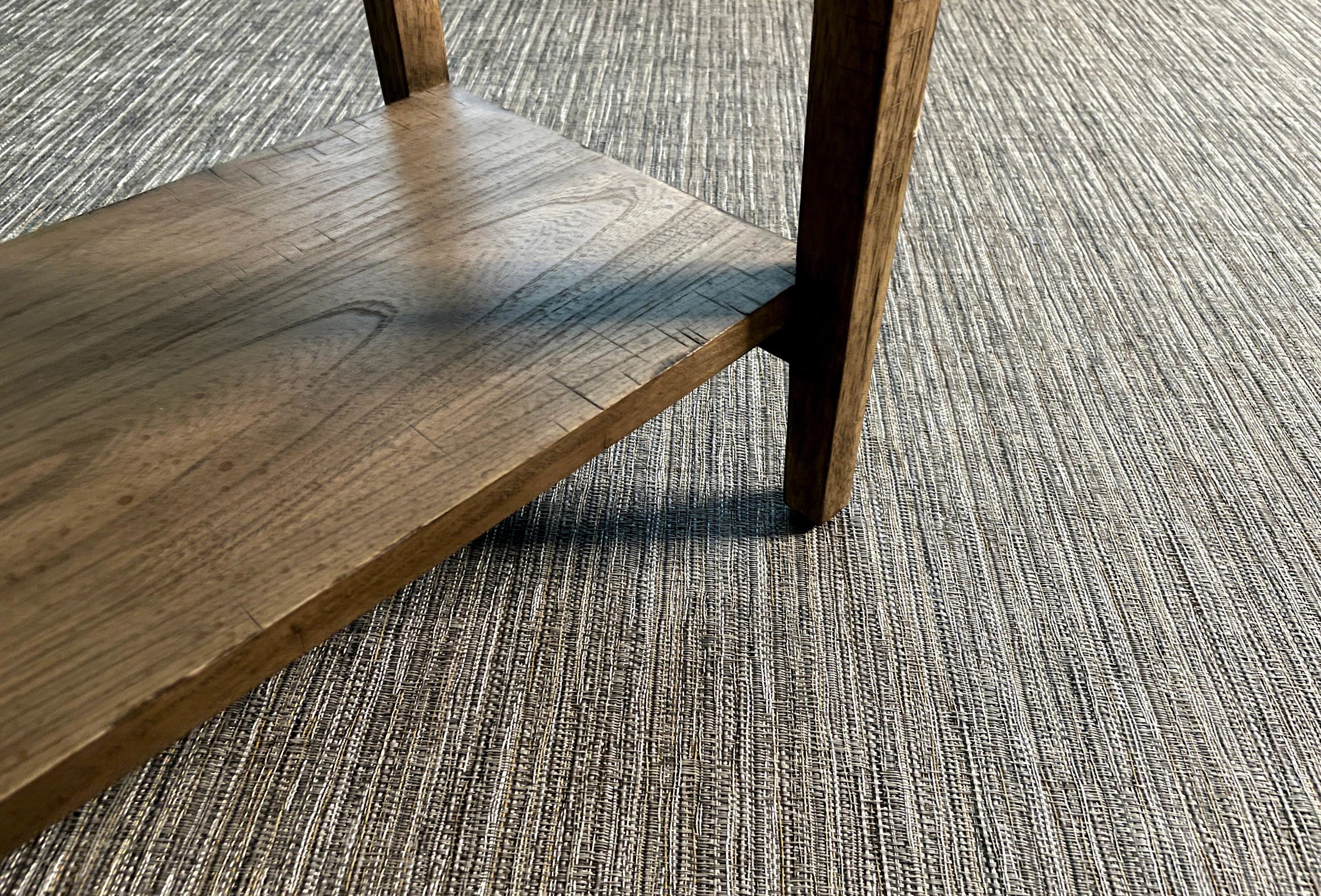 Close-up of wooden chair leg on textured gray carpet.