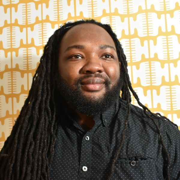 Man with long dreadlocks and a beard smiling.