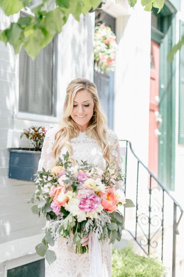 Blonde bride looking down at bouquet smiling