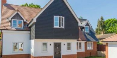 Modern two-story house with dark upper siding and white lower walls.
