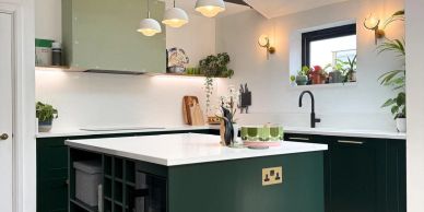 Modern green and white kitchen with an island and plants.